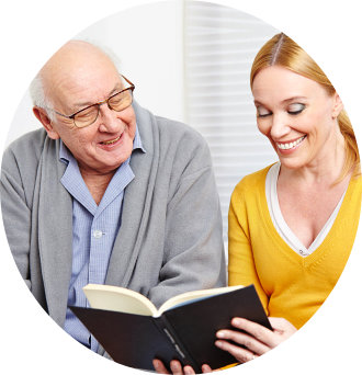 senior man reading book with caregiver