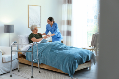 female caregiver serving a glass of water to her patient lying on bed