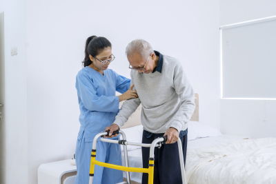 old man assisted by her caregiver to walk