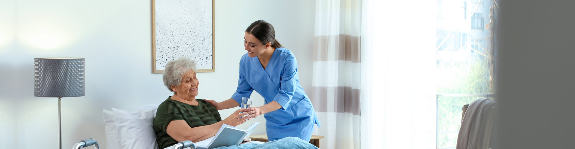 female caregiver serving a glass of water to her patient lying on bed